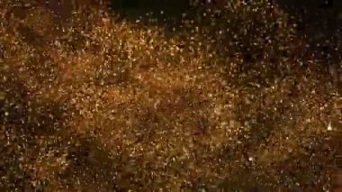 Siyah zemin üzerinde ışıldayan altın parçacıkların süper yavaş çekimi. Sığ odak derinliği. Yüksek hızlı sinema kamerası, 1000 fps..