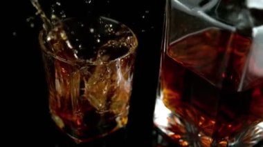 Buz küpünün viski içkisine düşmesi çok yavaş bir hareket. Hız rampası etkisi. Yüksek hızlı sinema kamerası, 1000 fps..