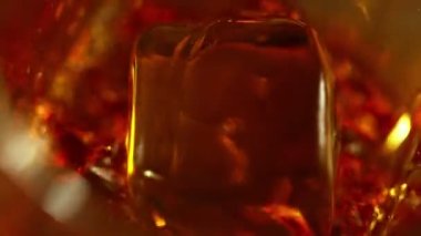 Süper makro çekimde buz küpünün viskiye dönüşmesi çok yavaş bir hareket. Hız rampası etkisi. Yüksek hızlı sinema kamerası, 1000fps