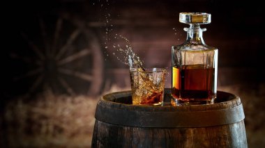 Freeze motion of ice cube falling into whisky shot. Still life beverages background with free space fort text. Vintage interior of village barn. clipart
