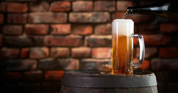 Pouring beer into pint, stylish brick wall on background. Fresh beverages and pub backgorund.