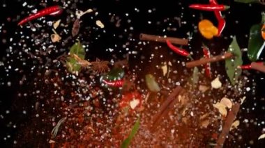 Uçan baharatların süper yavaş çekimi siyah arka planda karışır. Yüksek hızlı sinema kamerası, 1000 fps. Hız rampası etkisi.