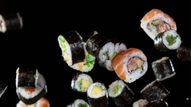 Siyah arka planda uçan suşi parçalarının süper yavaş çekimi. Hız rampası etkisi. Yüksek hızlı sinema kamerası, 1000fps