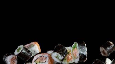 Siyah arka planda uçan suşi parçalarının süper yavaş çekimi. Yüksek hızlı sinema kamerası, 1000fps