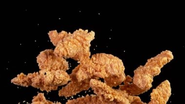 Siyah arka planda uçan kızarmış tavuk parçaları. Yüksek hızlı sinema kamerası, 1000fps