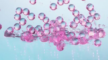 Pembe ve mavi hidrojel toplarının çok yavaş düşüşü. Kozmetik, gençlik ve güzellik konsepti. Yüksek hızlı sinema kamerası, 1000fps