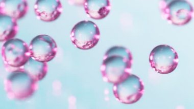 Pembe ve mavi hidrojel toplarının çok yavaş düşüşü. Kozmetik, gençlik ve güzellik konsepti. Yüksek hızlı sinema kamerası, 1000fps