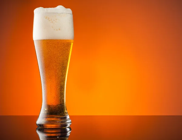Glass of beer with orange background — Stock Photo, Image