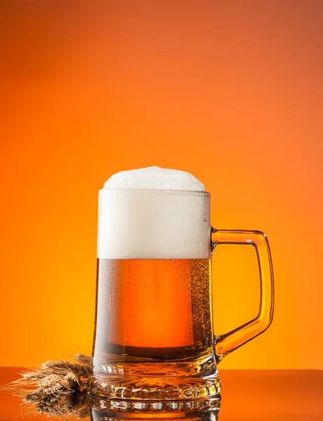 Glass of beer with orange background — Stock Photo, Image