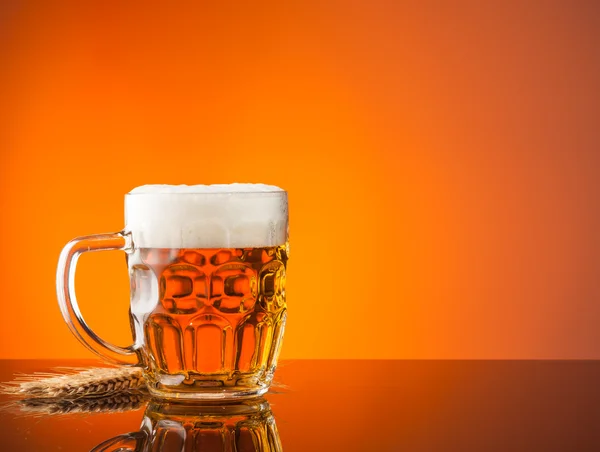 Glass of beer with orange background — Stock Photo, Image