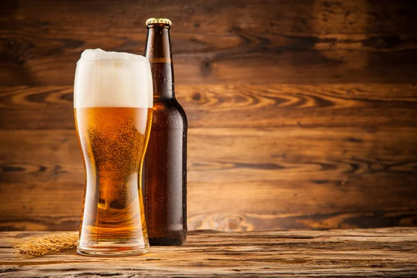 Copo e garrafa de cerveja em tábuas de madeira — Fotografia de Stock