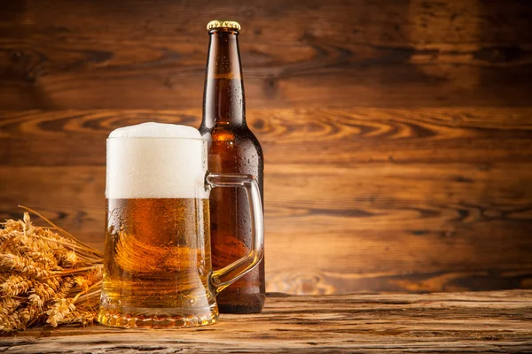 Verre et bouteille de bière sur planches de bois — Photo