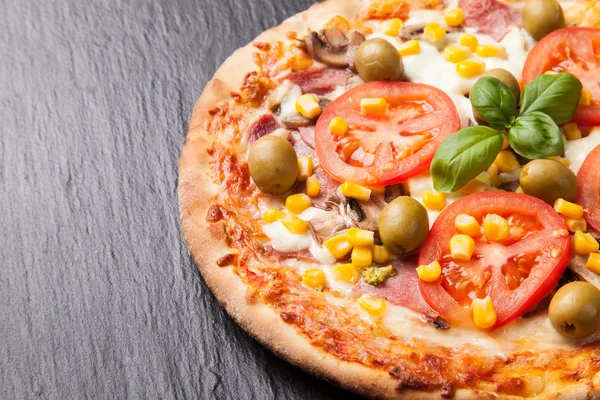 Delicious fresh pizza served on black stone — Stock Photo, Image