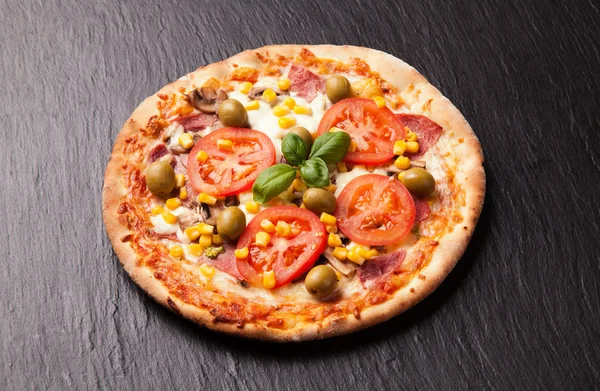 Delicious fresh pizza served on black stone — Stock Photo, Image