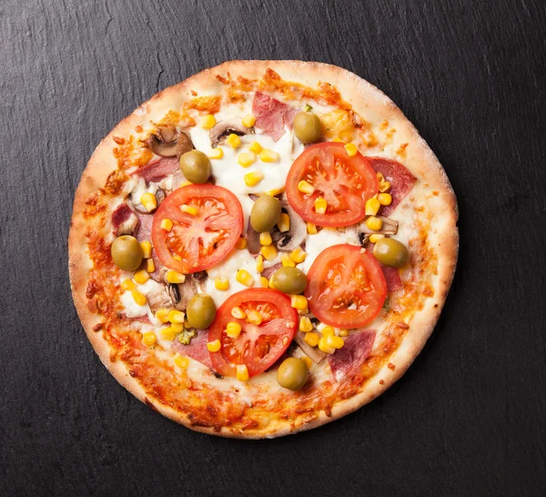 Delicious fresh pizza served on black stone — Stock Photo, Image