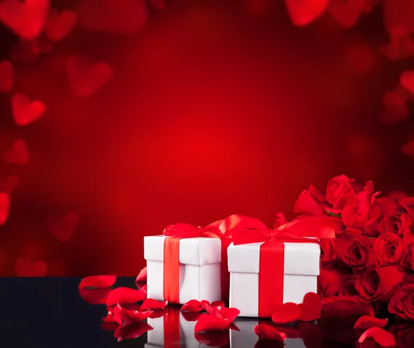 Gifts with roses on black glass table — Stock Photo, Image