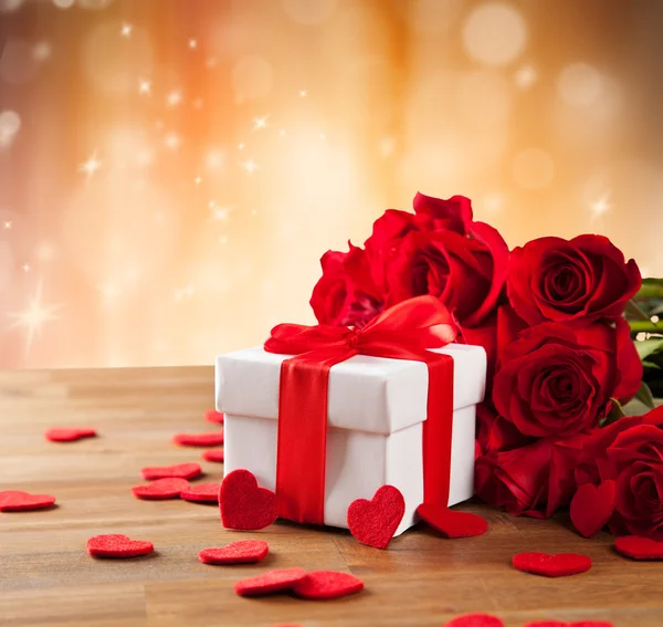 Gift with roses on wooden table — Stock Photo, Image