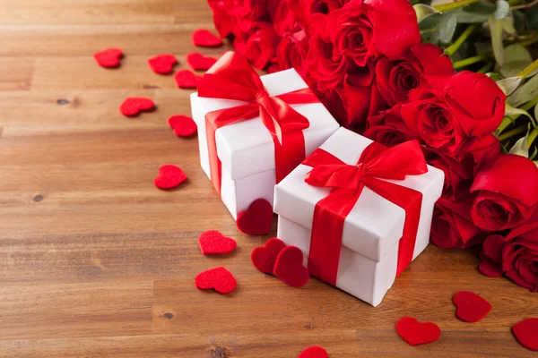 Presentes com rosas na mesa de madeira — Fotografia de Stock