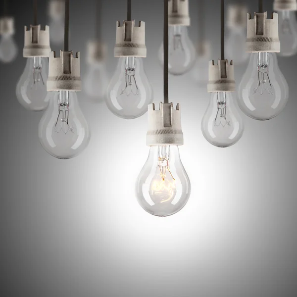 Light bulbs in row with single one shinning Stock Picture