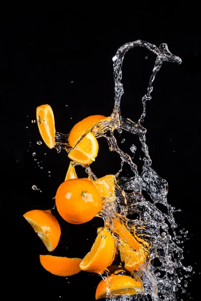 Laranjas com salpicos de água no fundo preto — Fotografia de Stock