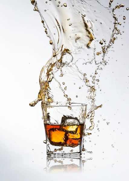 Whiskey drink with splash and ice cubes — Stock Photo, Image