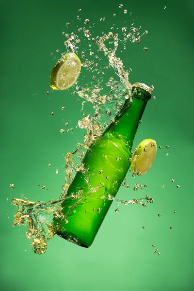 Flaska frukt öl med plask, på gree — Stockfoto