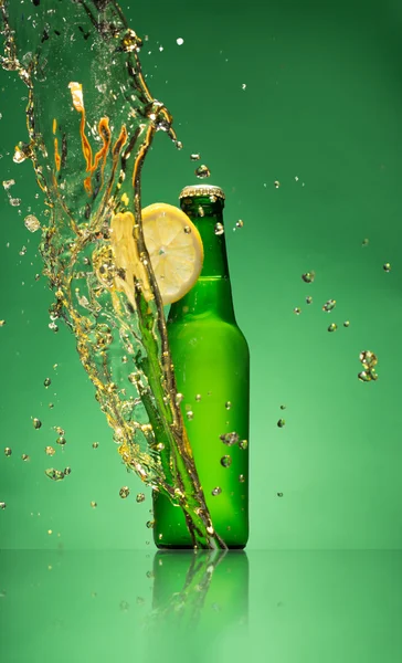 Bottle of fruit beer with splash, on gree — Stock Photo, Image