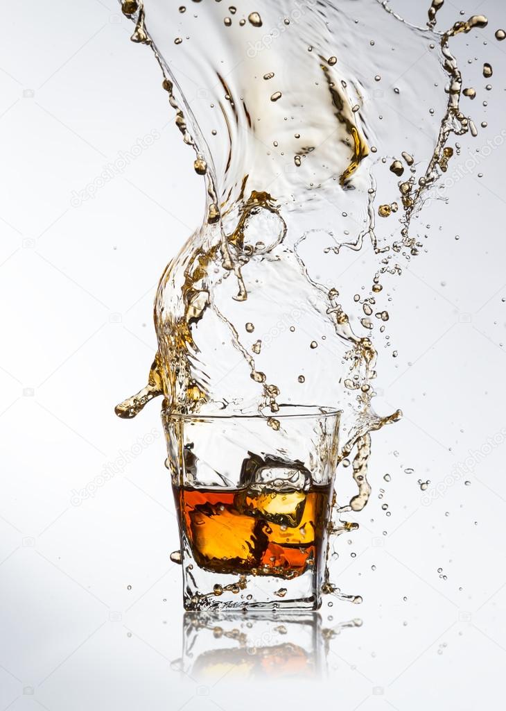 Whiskey drink with splash and ice cubes