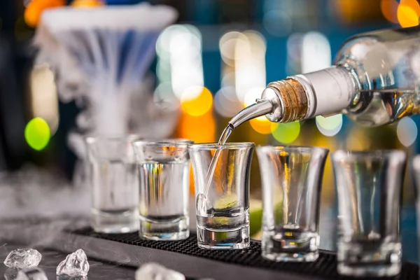 Barman vertiendo el espíritu duro en los vasos — Foto de Stock