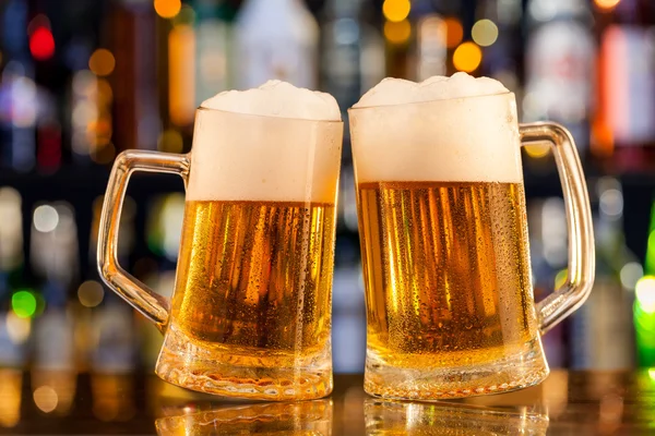 Jugs of beer served on bar counter — Stock Photo, Image