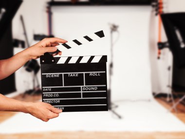 Man with film clapper in studio clipart