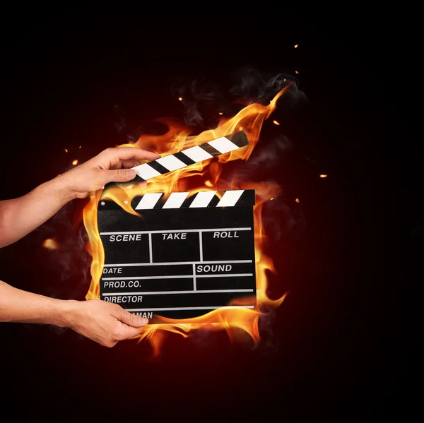 Man with film clapper in fire — Stock Photo, Image