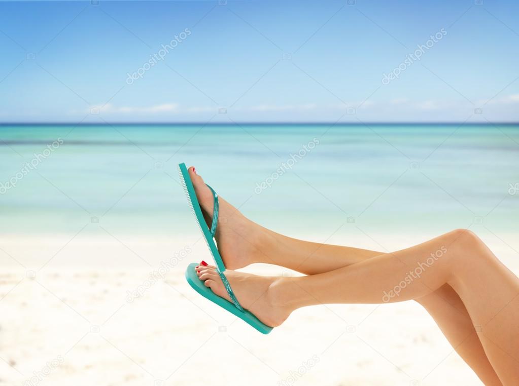 Slim female legs on sandy beach