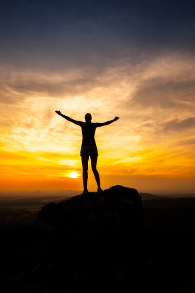 Силуэт одинокой взрослой женщины на камне
