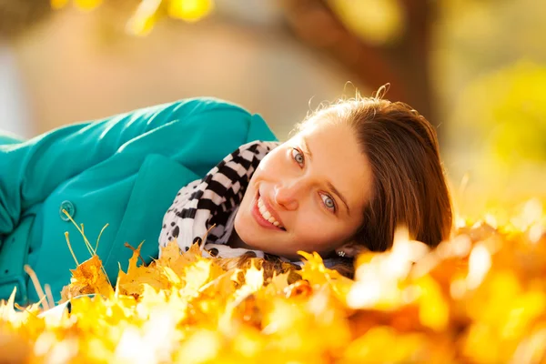 Beautiful girl lying in autumn leaves — Stock Photo, Image