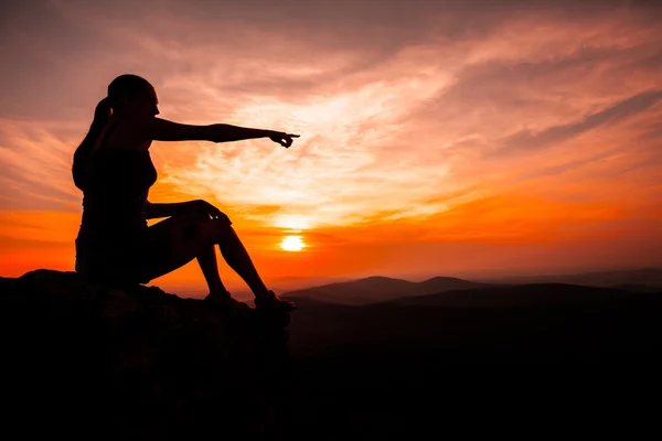 Silhouette einer Frau, die den Sonnenuntergang beobachtet und zeigt — Stockfoto