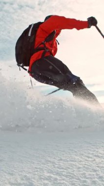 Tepeden aşağı koşan beleş kayakçı. Dondurma Hareketi. Kar tozu patlıyor. Mavi Gök 'le güneşli bir gün. Dikey Görünüm Oranı.