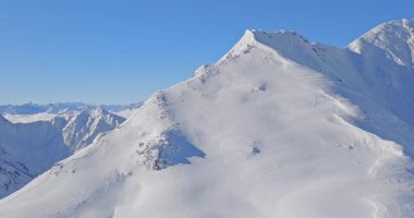 Avusturya 'da karlı bir dağ sırtından yükselen bir kayakçının hava görüntüleri. Kış manzarası, taşra macerası ve 4K 'da çekilen nefes kesici dağ manzarasında yalnızlık..