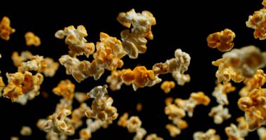 Uçan patlamış mısır parçalarının siyah arka planda dinamik makro çekimi. Kıtır ayrıntı ve hareket dramatik ve yüksek kontrastlı bir kompozisyonda yakalanır. Reklam ve yaratıcı tasarım için mükemmel..