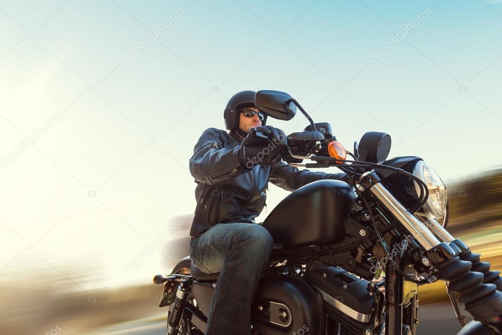 A young man riding a chopper on a road