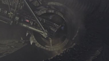 Açık bir kömür madeninde çalışan büyük bir kova tekerleği kazıcısının havadan yakın çekimi. Dönüşümlü kazı kolu sürekli olarak toprak ve kömür çıkartır ve etkin bir şekilde taşıyıcı bantlara malzeme aktarır.