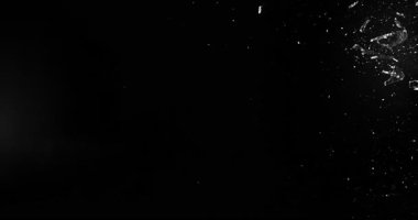 Uçan parçalar ve siyah arka planda izole edilmiş toz ile yan görüş. Çarpışma veya geçiş için mükemmel VFX eşleştirme ögesi.