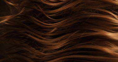 Dalgalı kahverengi saçların soyut dokusu zarif doğal dalgalar ve kıvrımlar oluşturuyor. Organik hareket, yumuşak ışık ve zengin tonlar sinematik güzellik arkaplanı ya da lüks görsel element oluşturur.