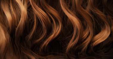 Dalgalı kahverengi saçların soyut dokusu zarif doğal dalgalar ve kıvrımlar oluşturuyor. Organik hareket, yumuşak ışık ve zengin tonlar sinematik güzellik arkaplanı ya da lüks görsel element oluşturur.