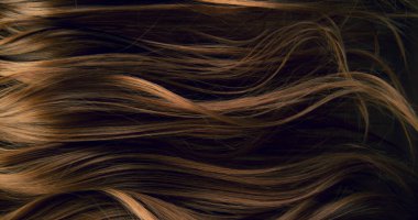 Dalgalı kahverengi saçların soyut dokusu zarif doğal dalgalar ve kıvrımlar oluşturuyor. Organik hareket, yumuşak ışık ve zengin tonlar sinematik güzellik arkaplanı ya da lüks görsel element oluşturur.