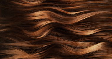 Dalgalı kahverengi saçların soyut dokusu zarif doğal dalgalar ve kıvrımlar oluşturuyor. Organik hareket, yumuşak ışık ve zengin tonlar sinematik güzellik arkaplanı ya da lüks görsel element oluşturur.