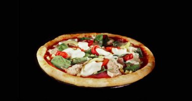 Pişirme işlemi sırasında pizza dönüşümlü, siyah arka planda izole edilmiş. Sinema stüdyosunun çekimleri yemek pişirme süresinin ilerlemesini, erimiş peyniri ve taze malzemeleri gösteriyor. Yemek, yemek ve restoran kavramları için mükemmel..