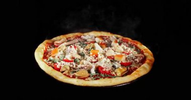 Pişirme işlemi sırasında pizza dönüşümlü, siyah arka planda izole edilmiş. Sinema stüdyosunun çekimleri yemek pişirme süresinin ilerlemesini, erimiş peyniri ve taze malzemeleri gösteriyor. Yemek, yemek ve restoran kavramları için mükemmel..