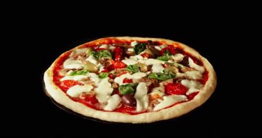 Pişirme işlemi sırasında pizza dönüşümlü, siyah arka planda izole edilmiş. Sinema stüdyosunun çekimleri yemek pişirme süresinin ilerlemesini, erimiş peyniri ve taze malzemeleri gösteriyor. Yemek, yemek ve restoran kavramları için mükemmel..