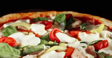 Pişirme işlemi sırasında pizza dönüşümlü, siyah arka planda izole edilmiş. Sinema stüdyosunun çekimleri yemek pişirme süresinin ilerlemesini, erimiş peyniri ve taze malzemeleri gösteriyor. Yemek, yemek ve restoran kavramları için mükemmel..